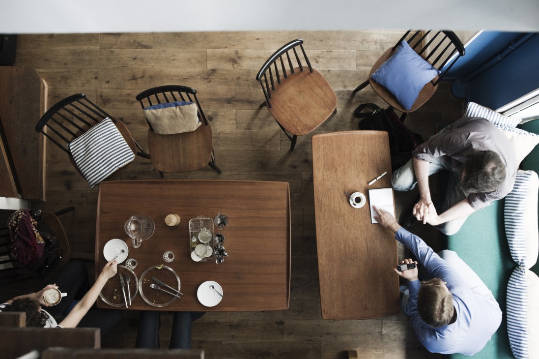 Overhead view of Merce and The Muse café in Paris with wooden tables, modern chairs, and customers dining.