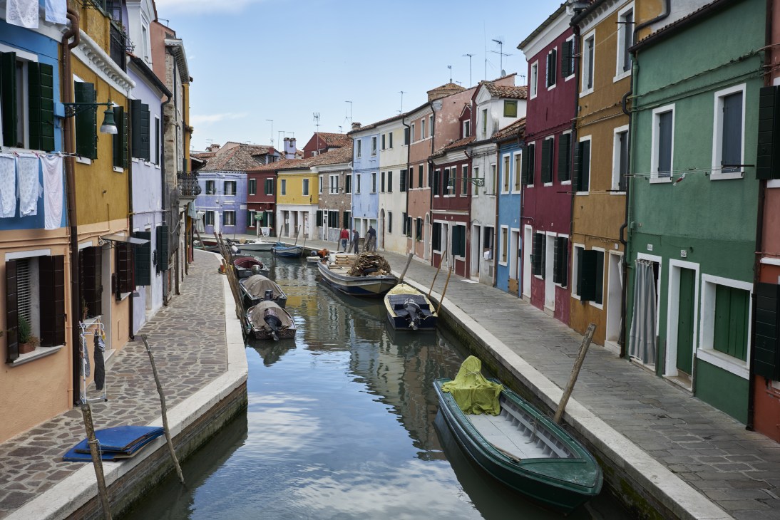 Canal lined with colorful buildings and moored boats in Murano, Venice