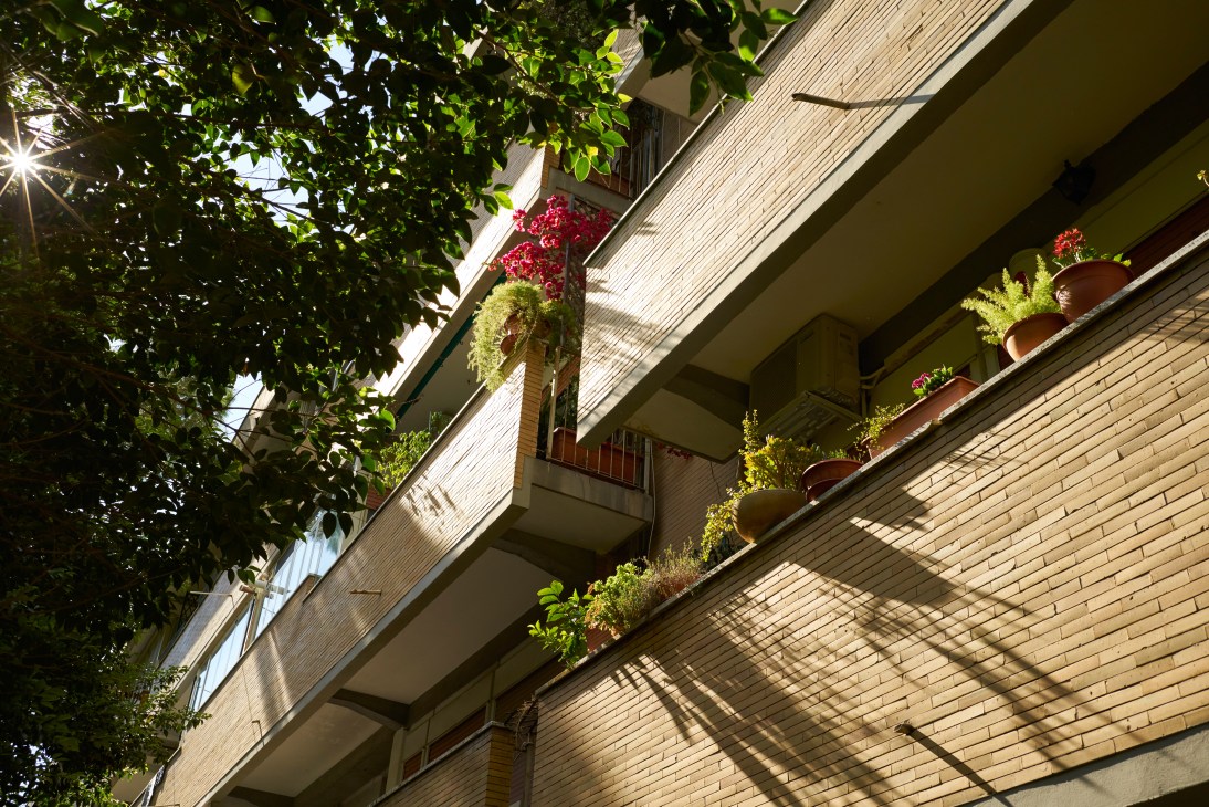 Modernist apartment building with flowering plants on balconies, brick facade and horizontal ribboning.