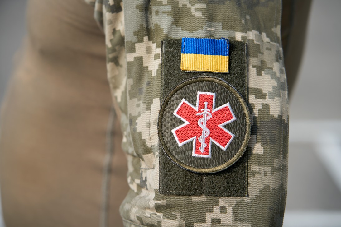 Ukrainian flag patch and red medical cross insignia on camouflage military uniform sleeve