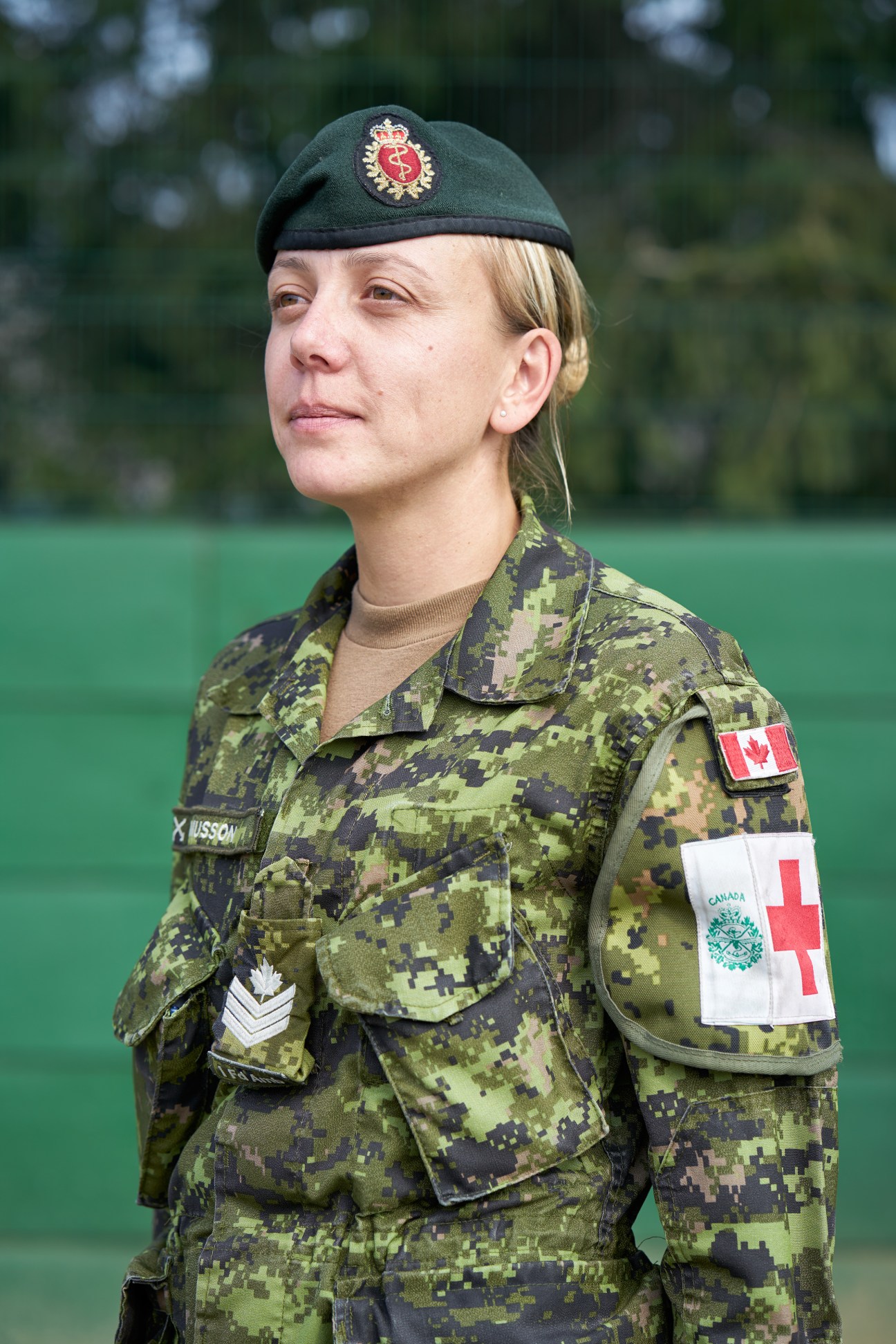 Canadian female soldier in digital camouflage uniform with medical cross patch and green beret