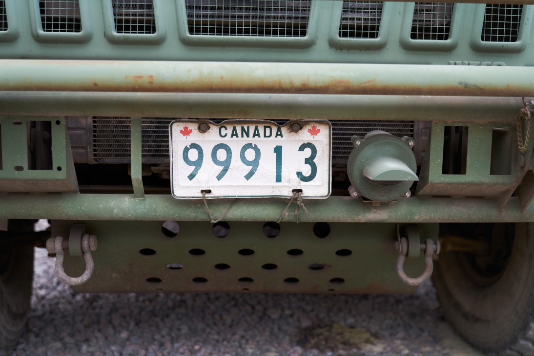 Close-up of a Canadian military vehicle's front end showing license plate 99913 and headlight