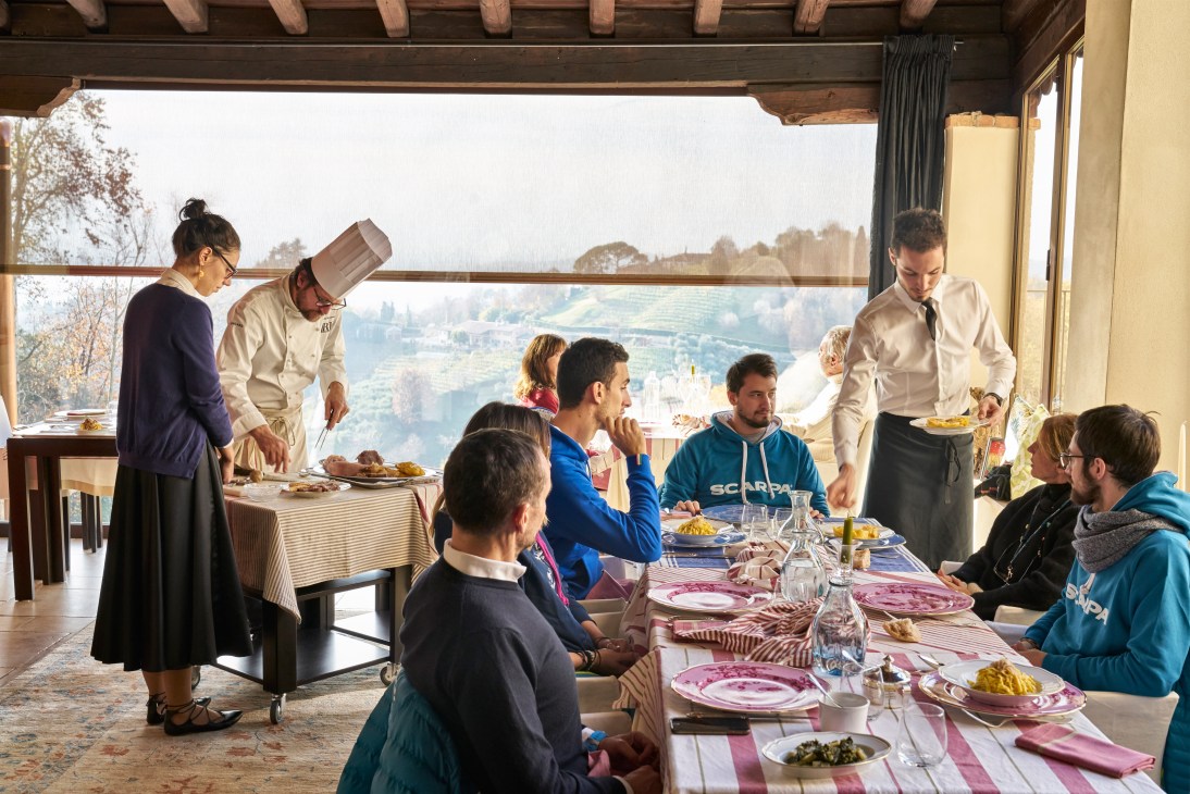Diners enjoying lunch at Trattoria Moderna Due Mori with panoramic valley views in background.