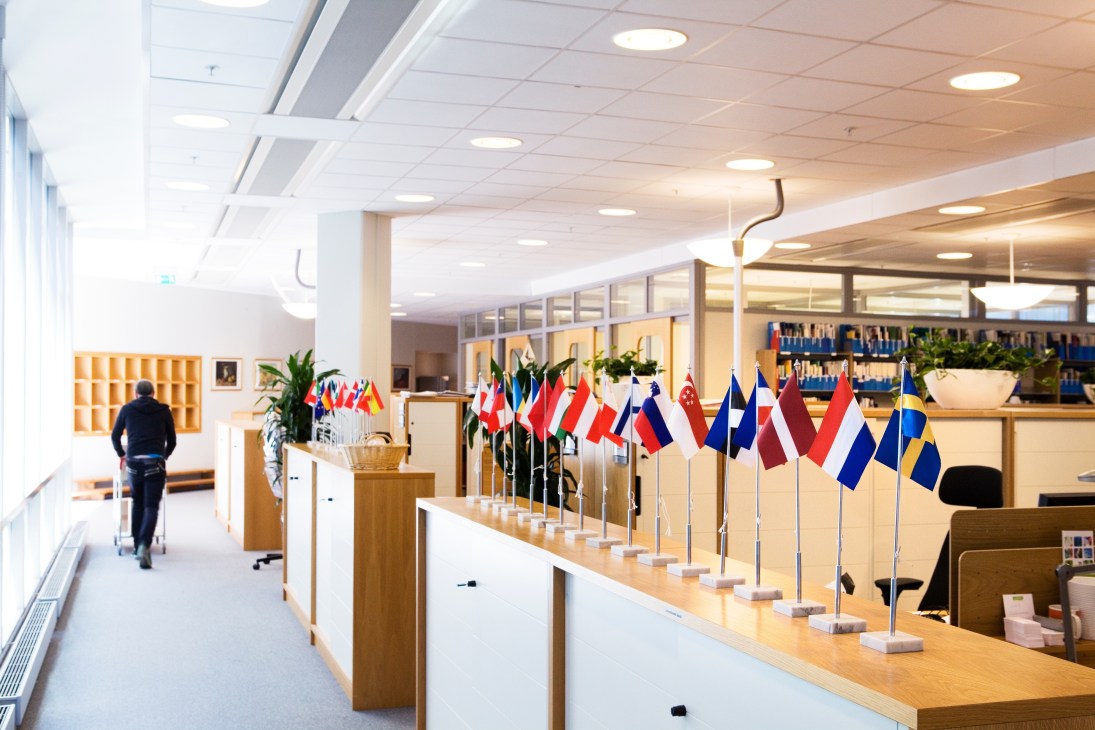 International office at Vinnova headquarters displaying multiple country flags on a wooden counter in Stockholm.