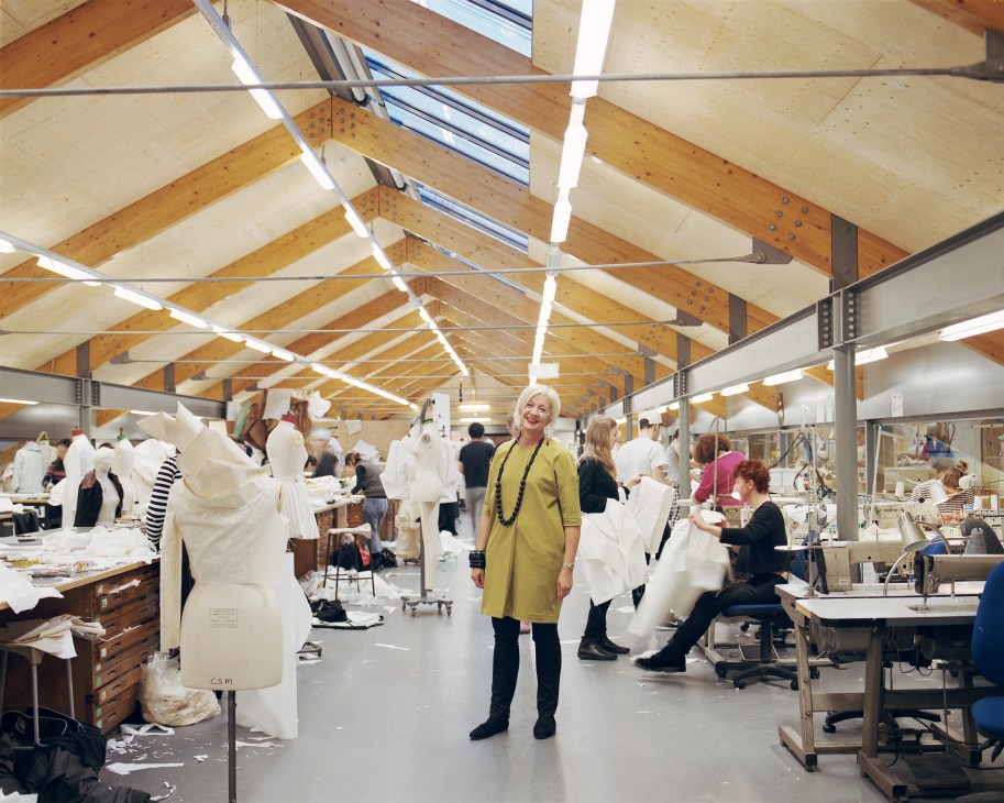 Anne Smith, dean of the School of Fashion and Textiles, stands in the womenswear studio surrounded by dress forms and students working at tables.