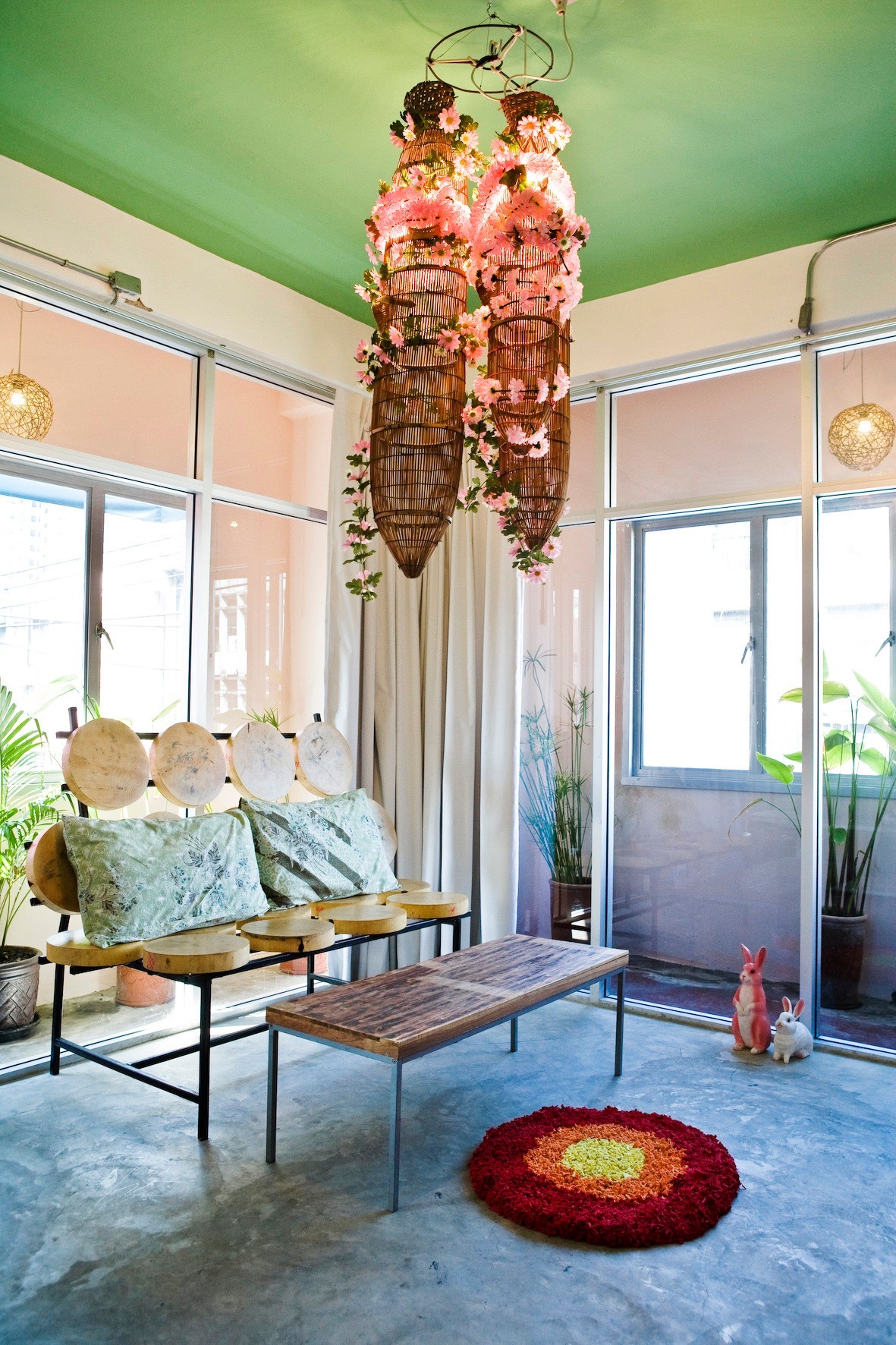 Interior of Mystic Palace hotel with green ceiling, hanging floral decorations, bench seating and colorful rug.