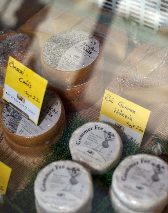 Local Swiss mountain cheese wheels and jars displayed with yellow price labels at a market.
