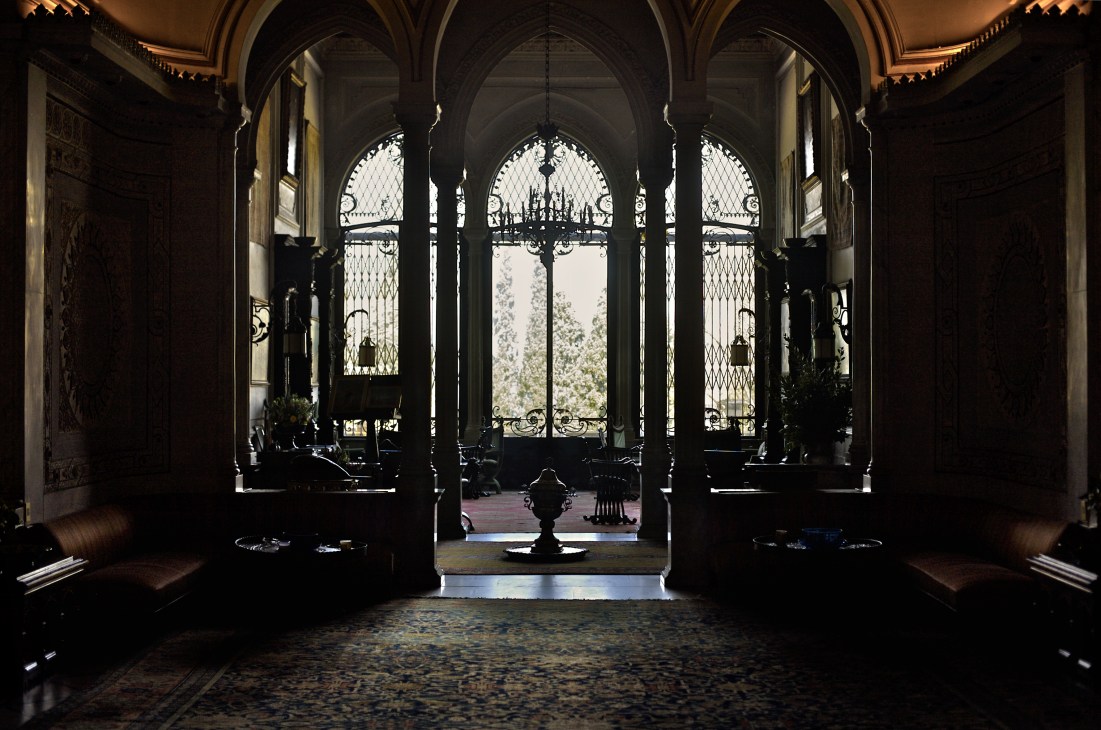 Ornate arched hall in Palais Sursock with decorative iron doors opening to a garden view.