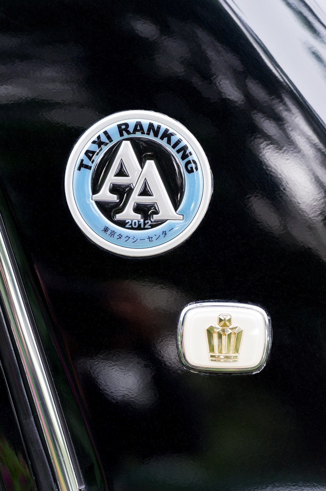 Close-up of taxi ranking emblem and crown logo on black vehicle door.