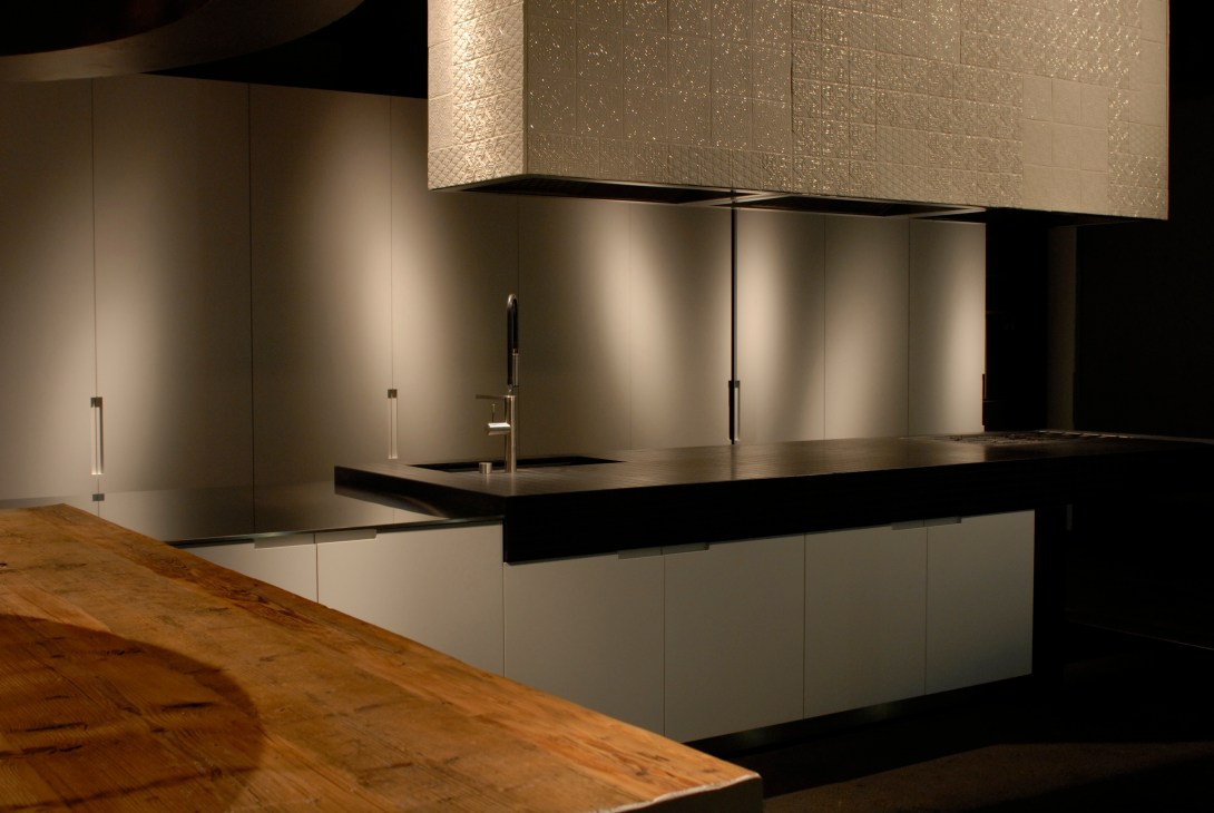 Boffi 'Duemilaotto' kitchen by Piero Lissoni with minimalist design featuring white cabinetry, black countertop, and textured backsplash.