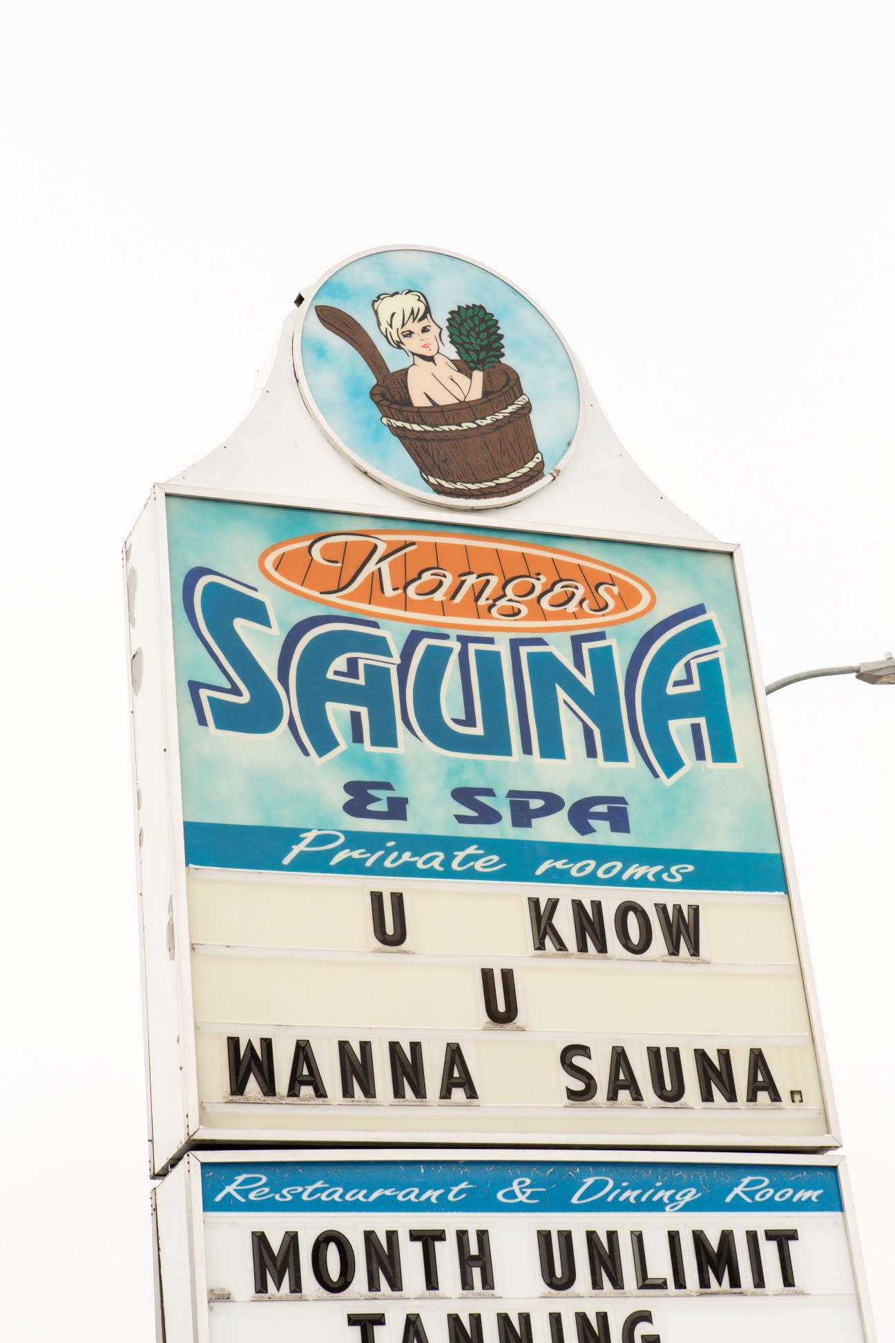 Vintage Kangas Sauna & Spa sign with illustration of woman in wooden bucket and changeable marquee text reading 'U KNOW U WANNA SAUNA'