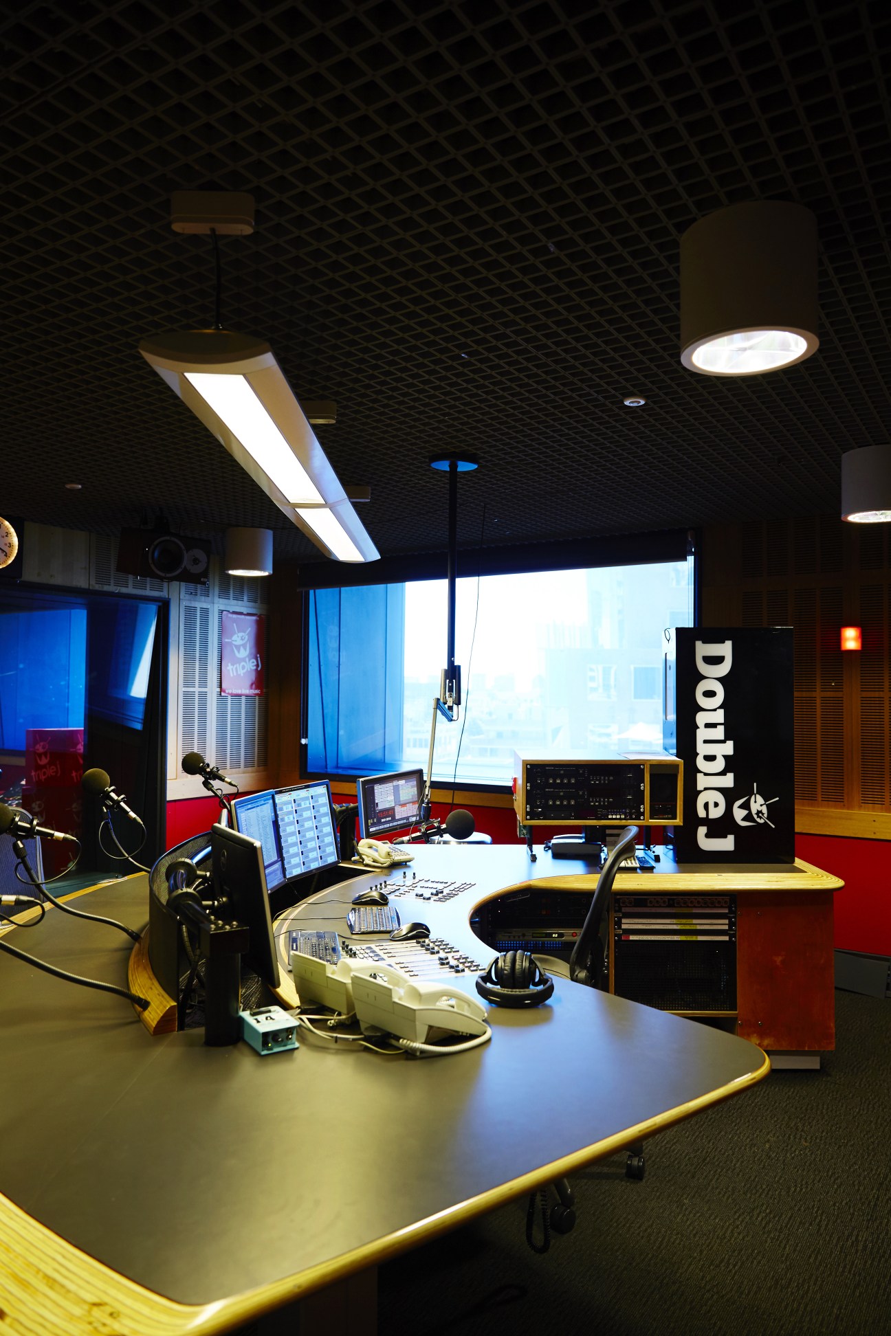 Double J radio studio with microphones, monitors, mixing equipment and control panels on curved desks.