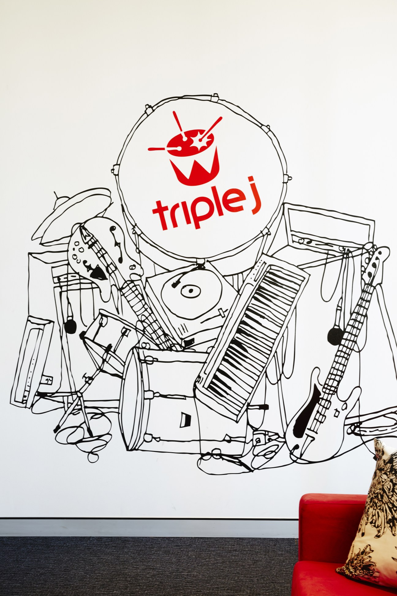 Triple J logo mural featuring red text and drum kit illustration in black line drawing style