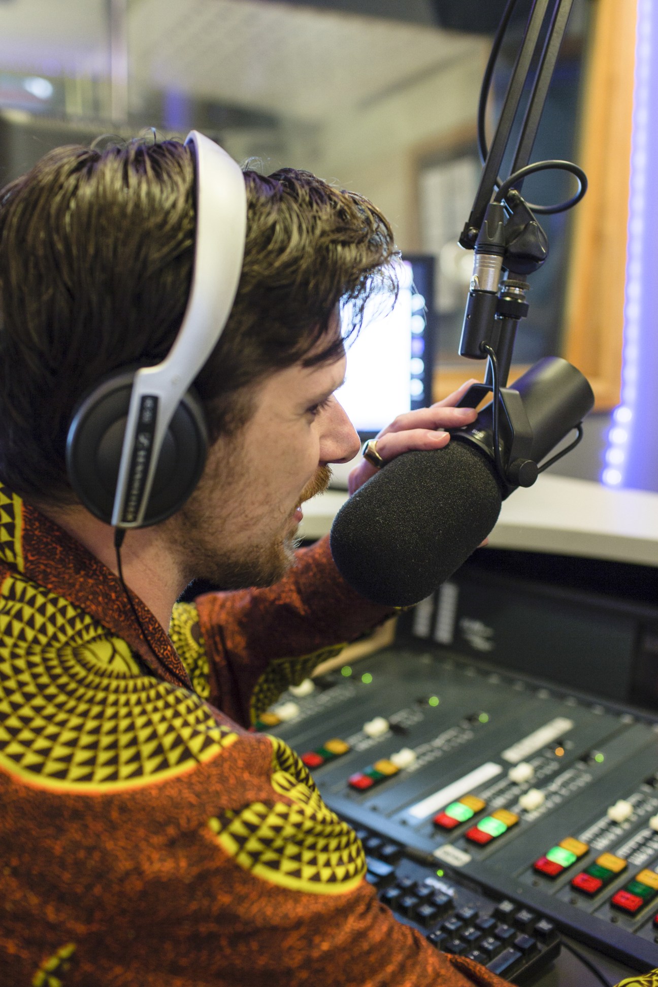 Marty Doyle speaks into a microphone wearing headphones in an FBI radio studio.