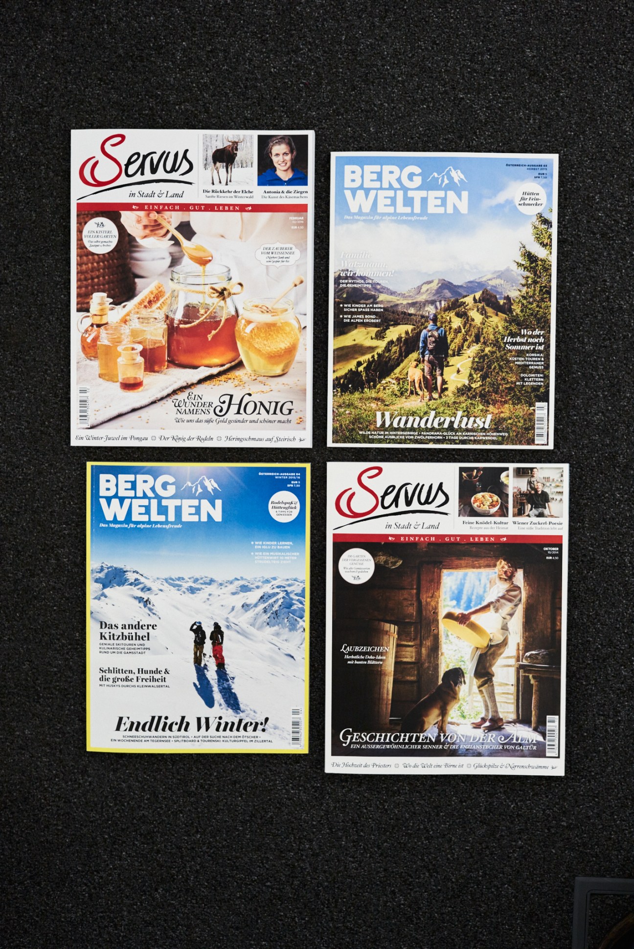 Magazine covers of Servus in Stadt & Land and Bergwelten displayed on dark background.
