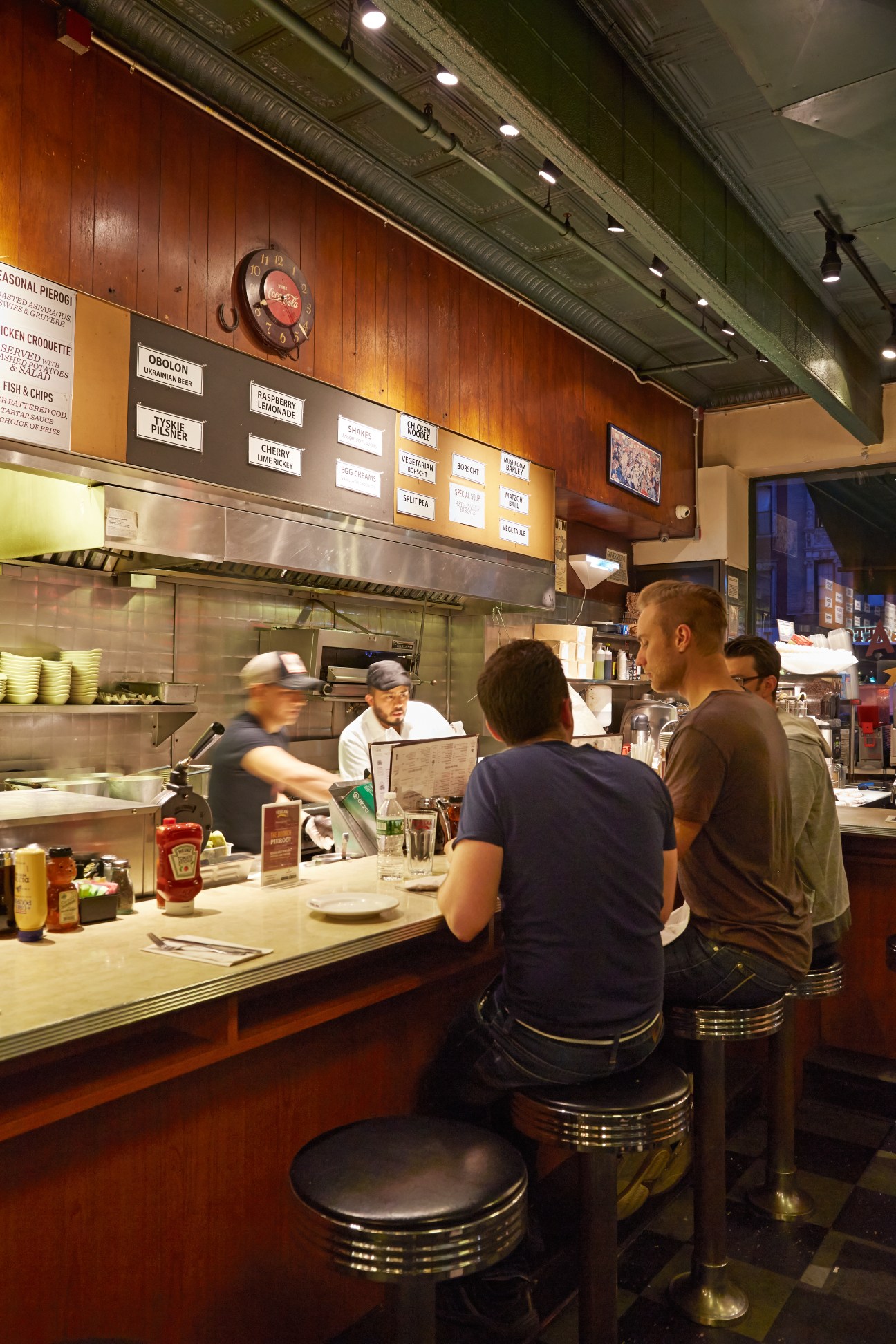 Customers sitting at counter of Veselka diner in New York with open kitchen visible behind
