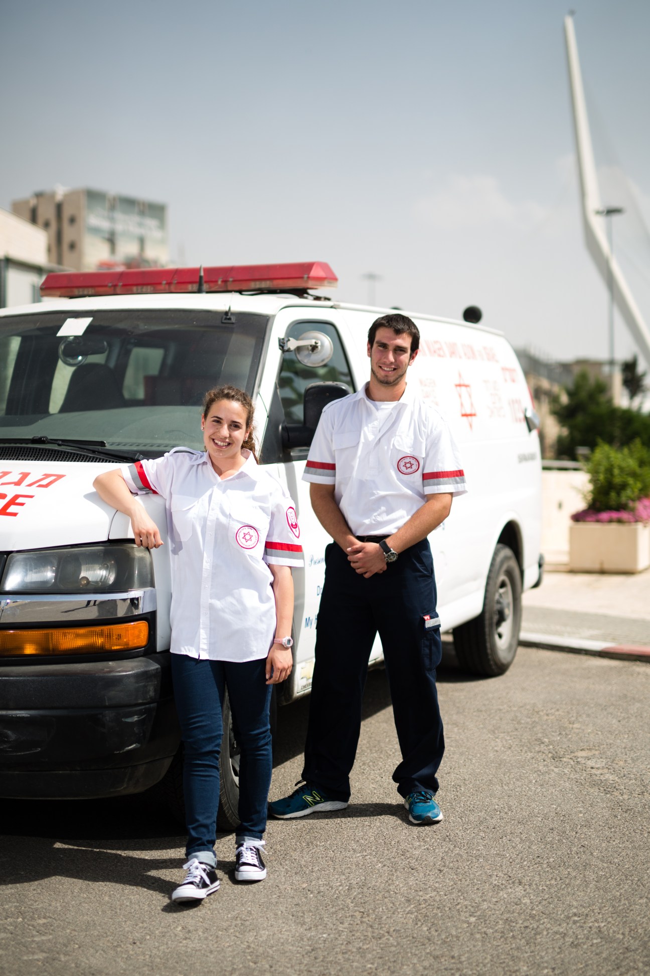 Two MDA paramedics in white uniforms stand beside ambulances in Jerusalem, ready to begin their shift.