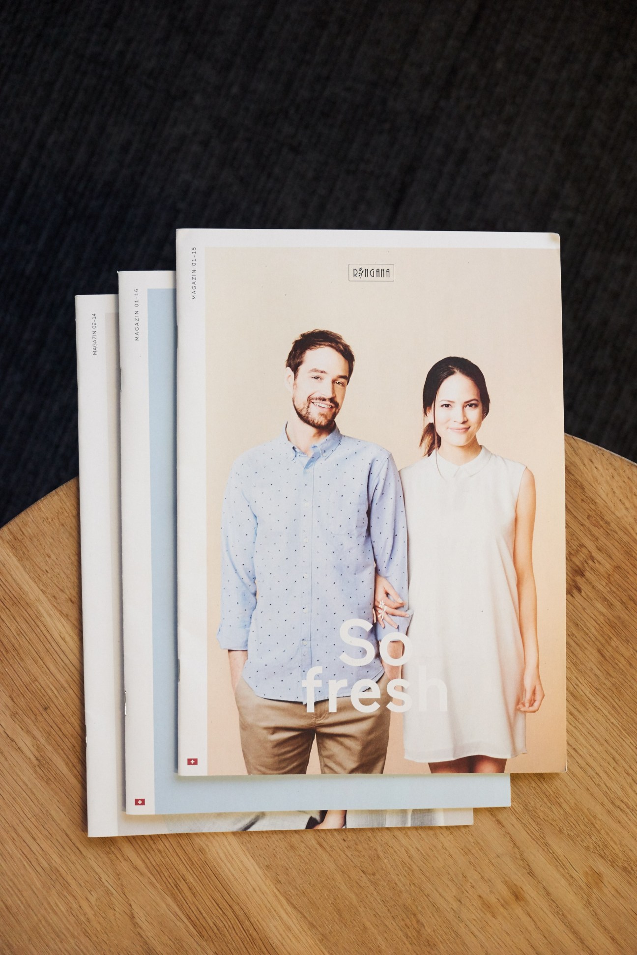 Stack of magazines featuring a cover with two people and the text 'so #res' on a wooden surface.