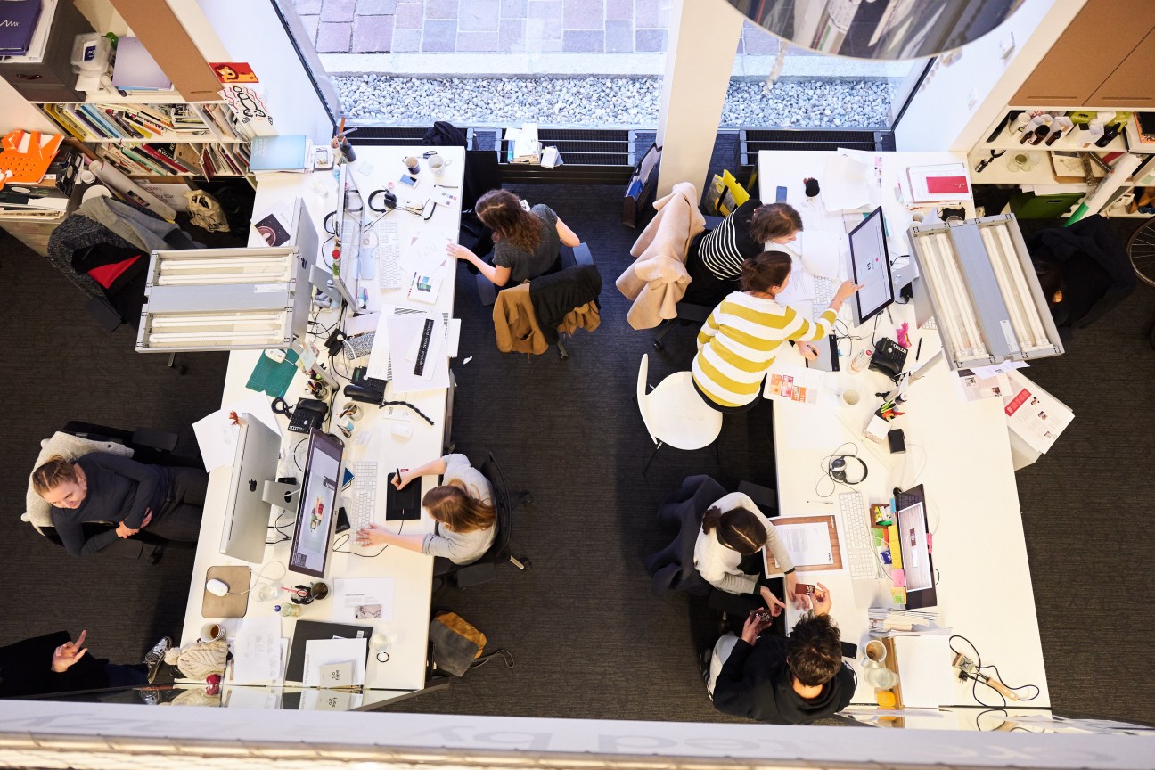 Overhead view of Moodley designers working at desks in a bright, modern office space with skylights.