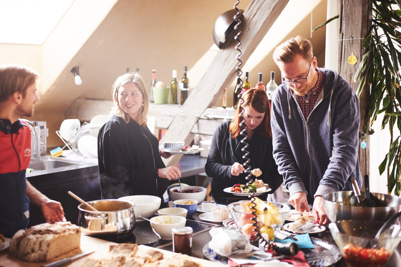 People sharing lunch at En Garde creative agency in Graz with food and wine in a bright attic space.