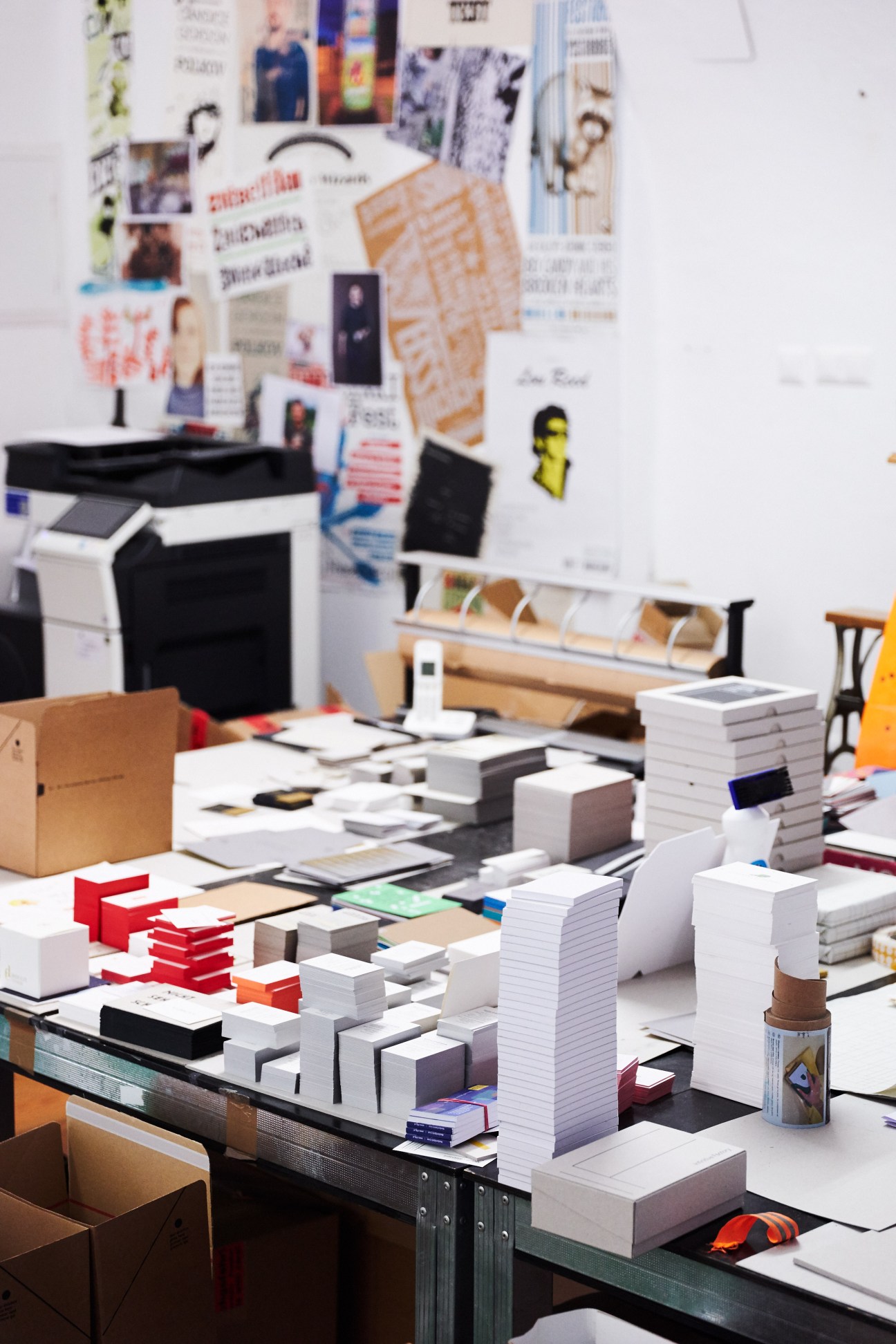 Design studio workspace with stacked business cards and printed materials displayed on desk.