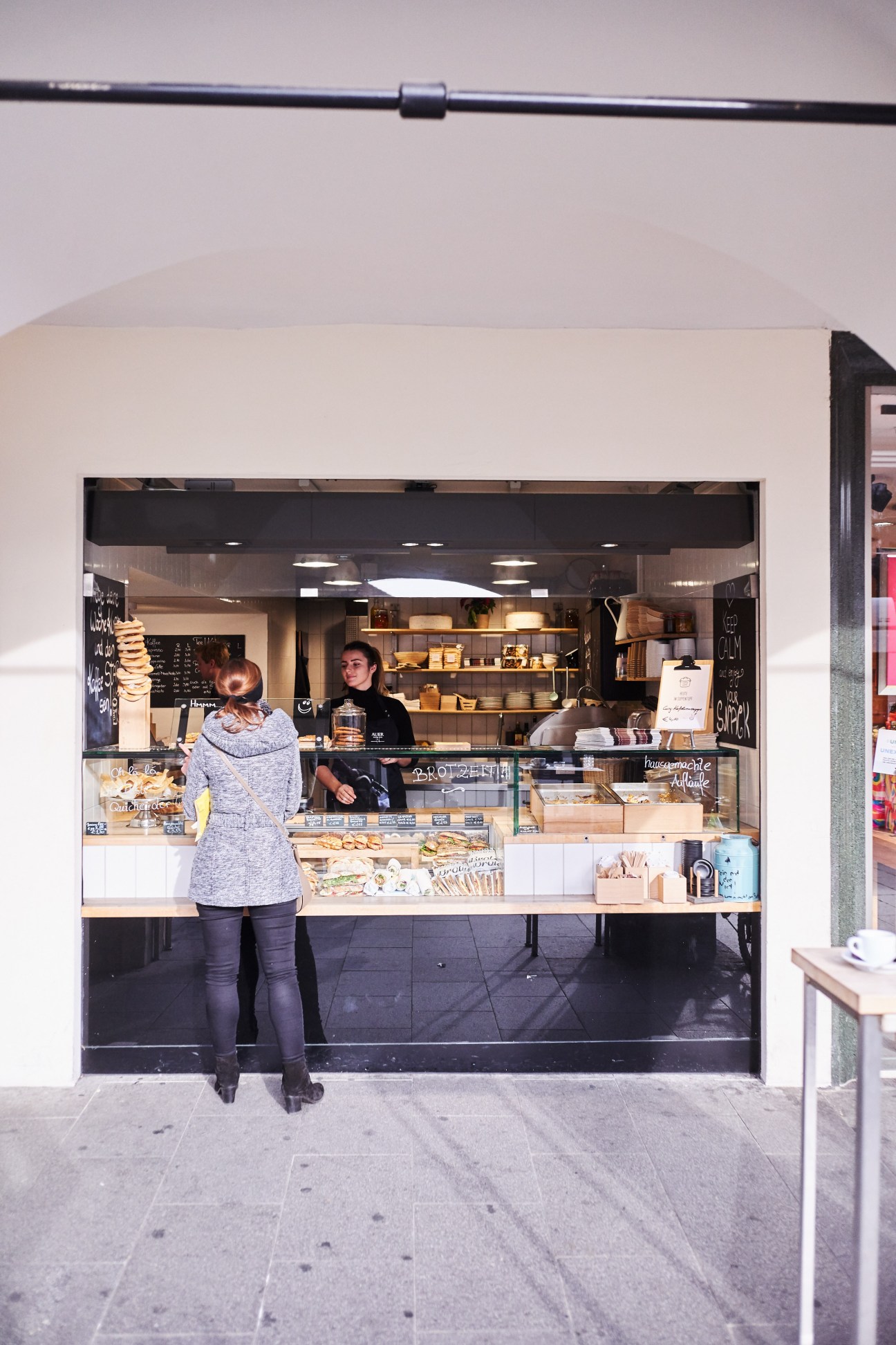 Customer ordering bread at Auer bakery counter in Graz with staff member behind the display.