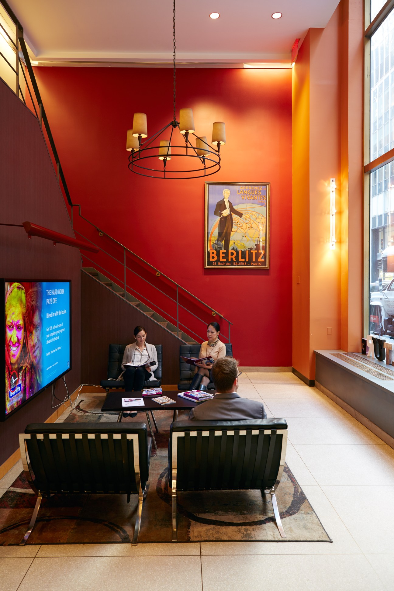 Berlitz reception at Rockefeller Centre with red walls, vintage language poster, and staff with students.