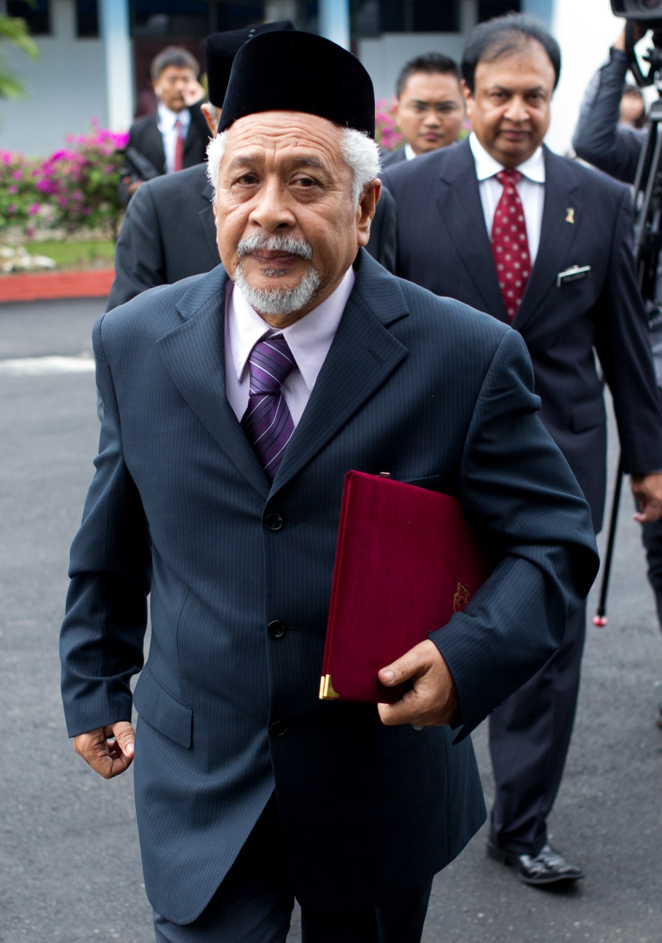Hassan Taib, a Malay Muslim insurgent negotiator, walks in formal attire with officials behind him.