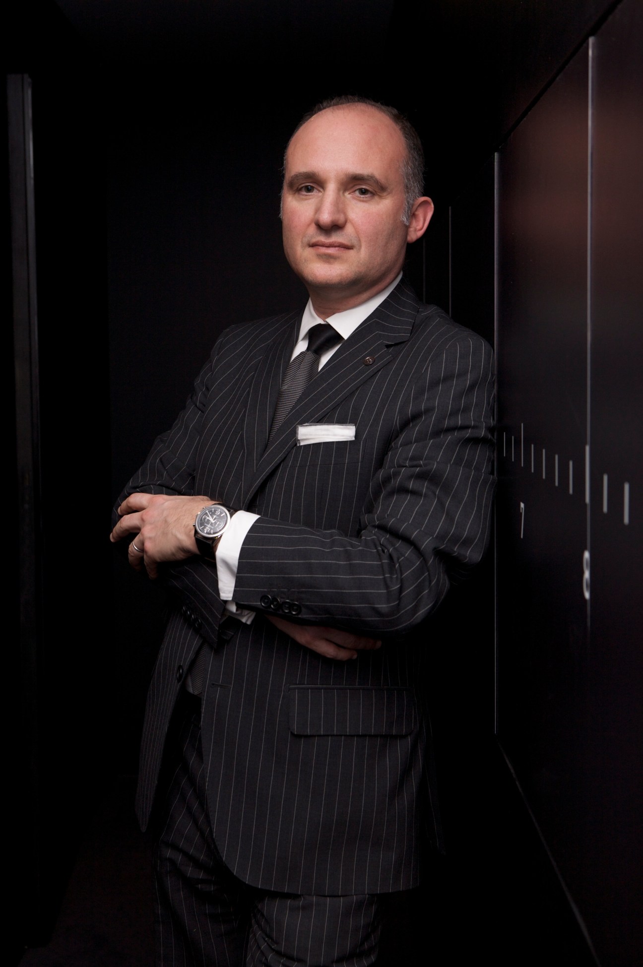 Carlos Rosillo, CEO of Bell & Ross, wearing a pinstriped suit and displaying a watch on his wrist.