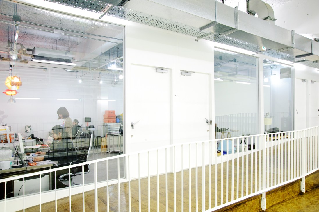 Modern office space with glass partitions and white railings at Tabloid workspace.
