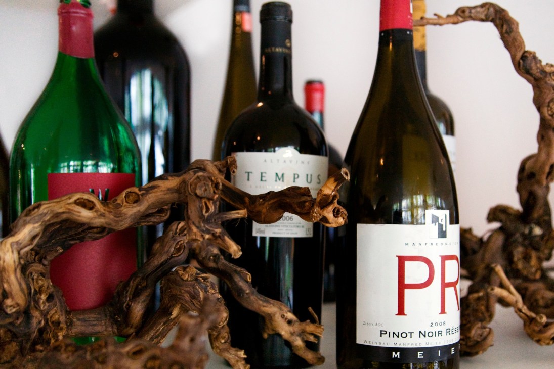 Wine bottles displayed with decorative wooden vine branches in foreground.