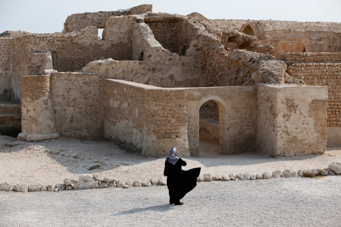Woman in black abaya visits ancient stone ruins of Harireh on Kish island.
