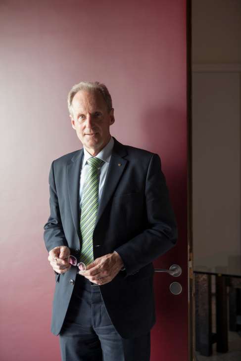 Wolfgang Schuster, Mayor of Stuttgart, wearing a dark suit and striped tie against a pink wall.