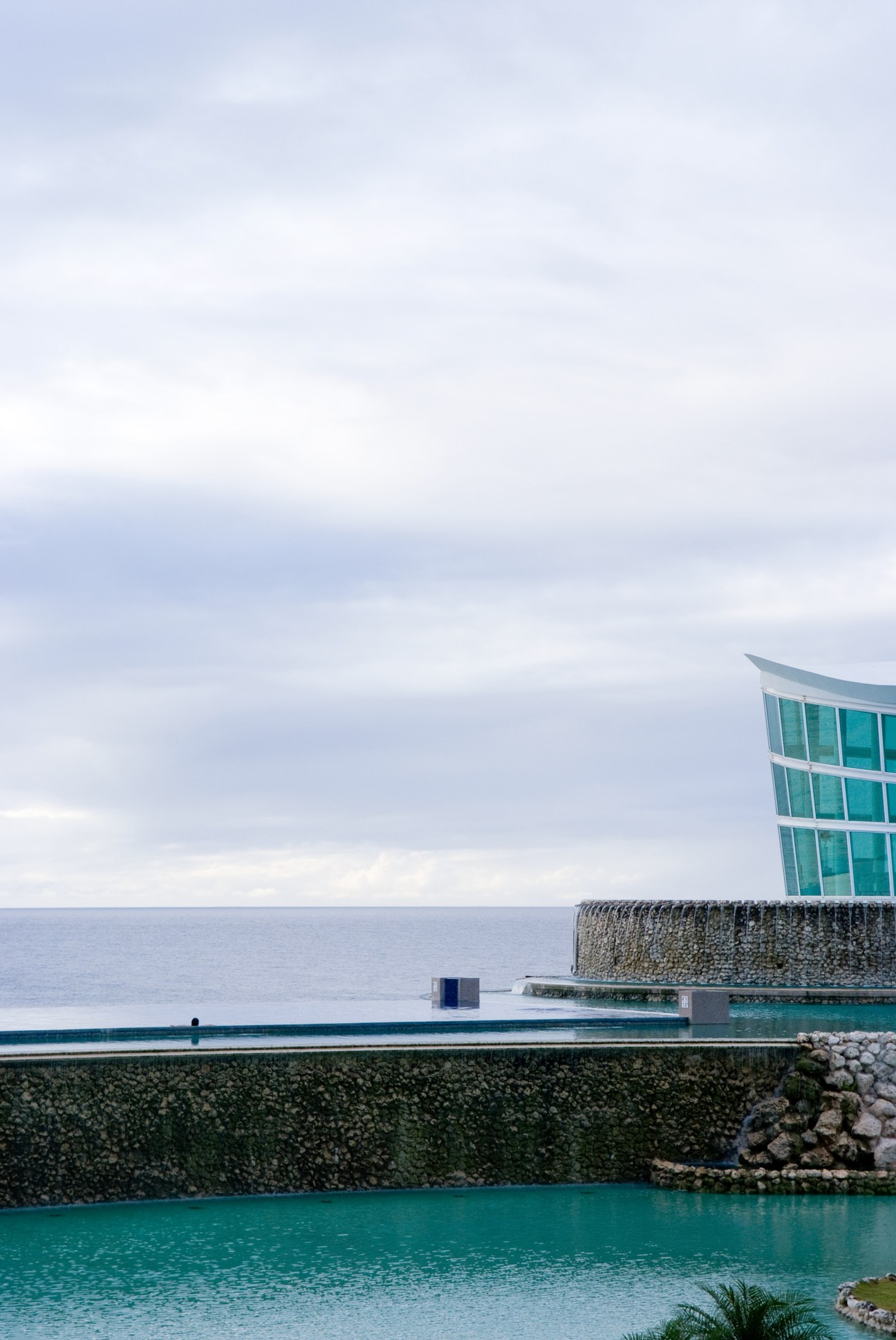 The Sheraton hotel's turquoise pool and modern building with sea view on Guam's coast.