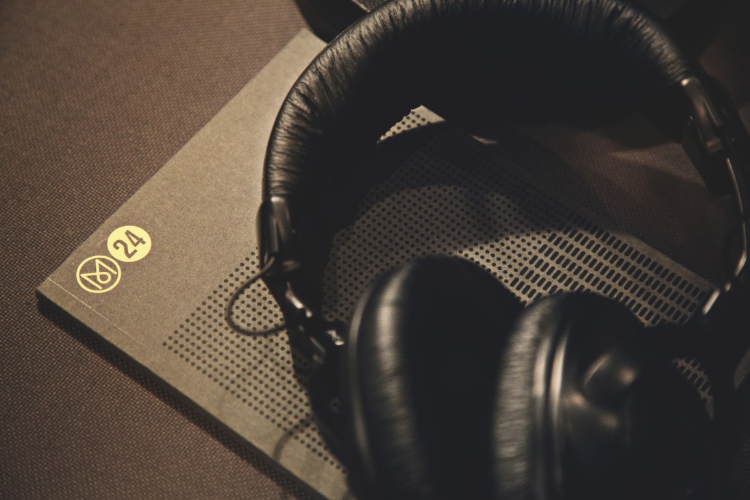 Monocle 24 branded notepad with headphones on textured surface.