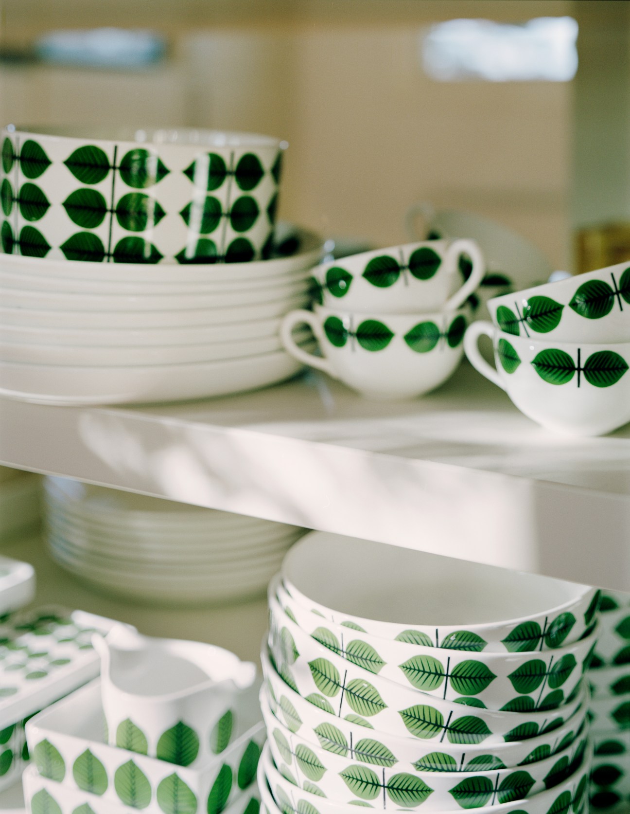 Gustavsberg crockery set with green leaf pattern on white dishes including bowls, cups and plates.