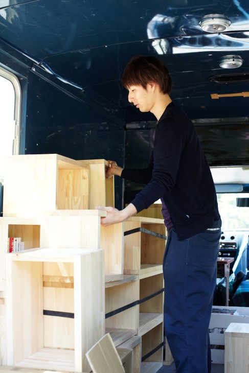 Shuhei Mita arranges wooden book shelving inside his mobile Book Truck in Tokyo.