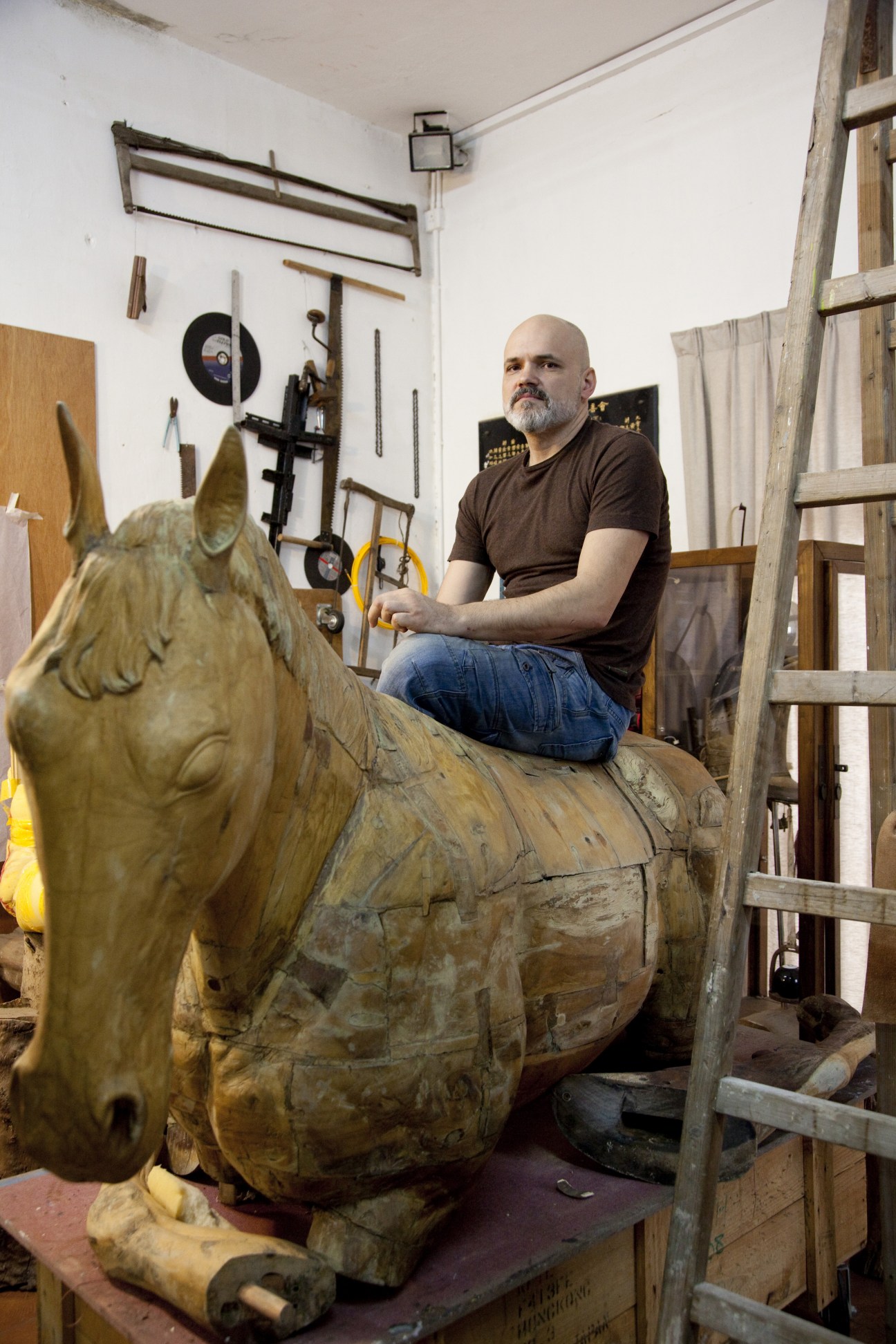 Russian painter and sculptor Konstantin Bessmertny in his studio with wooden horse sculpture