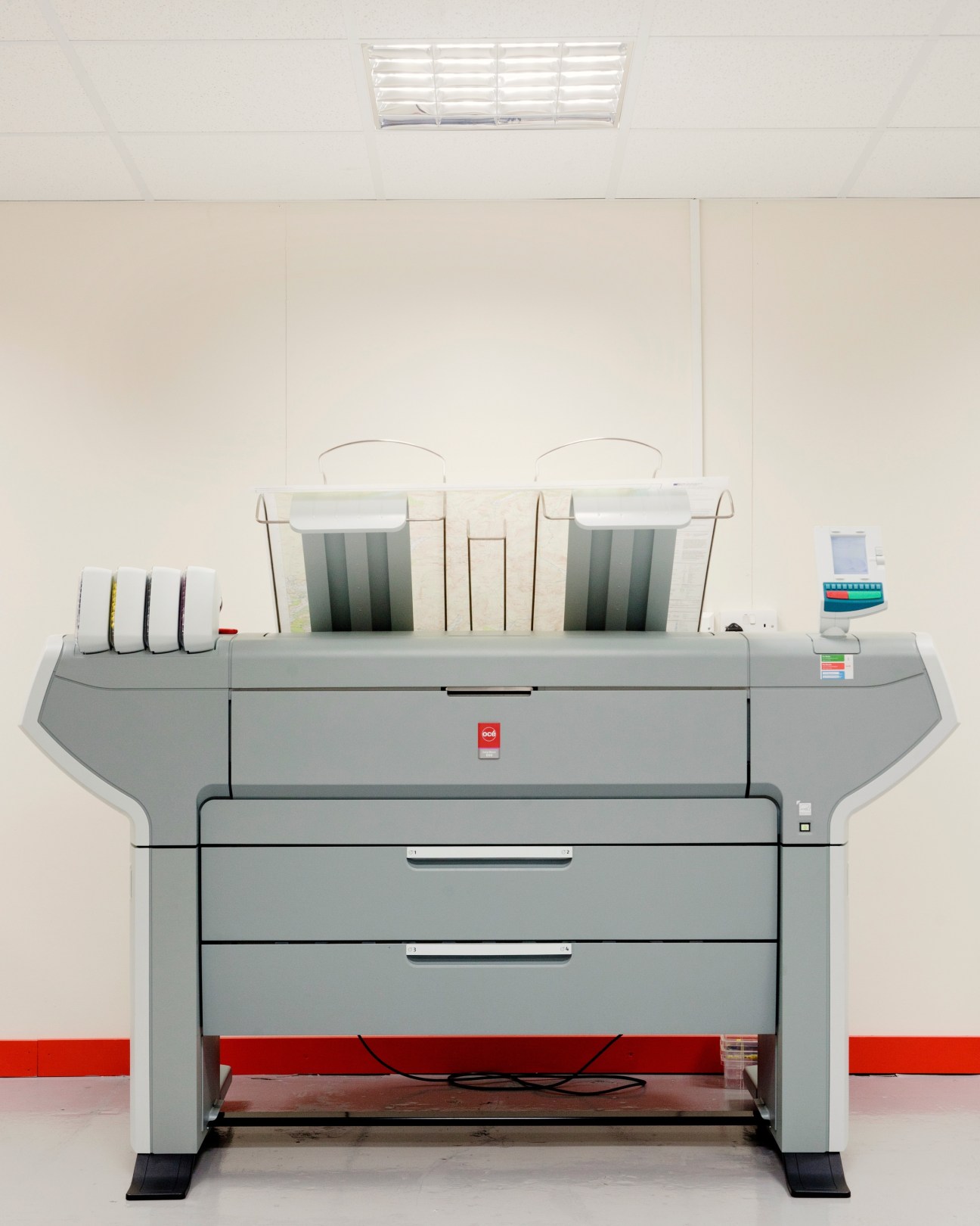 Industrial inkjet printer with gray body, red base panel, and tape dispensers mounted on side.