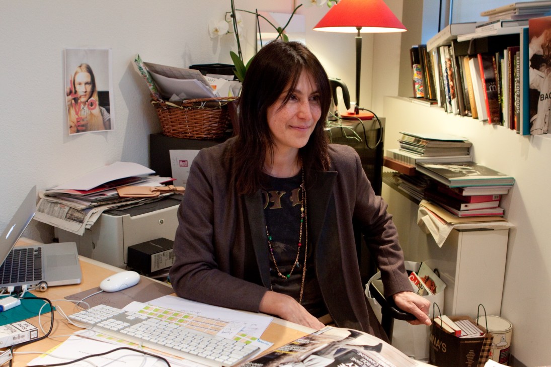 Fashion and lifestyle editor Elisabeth Lazaroo sitting at her desk surrounded by books and magazines.