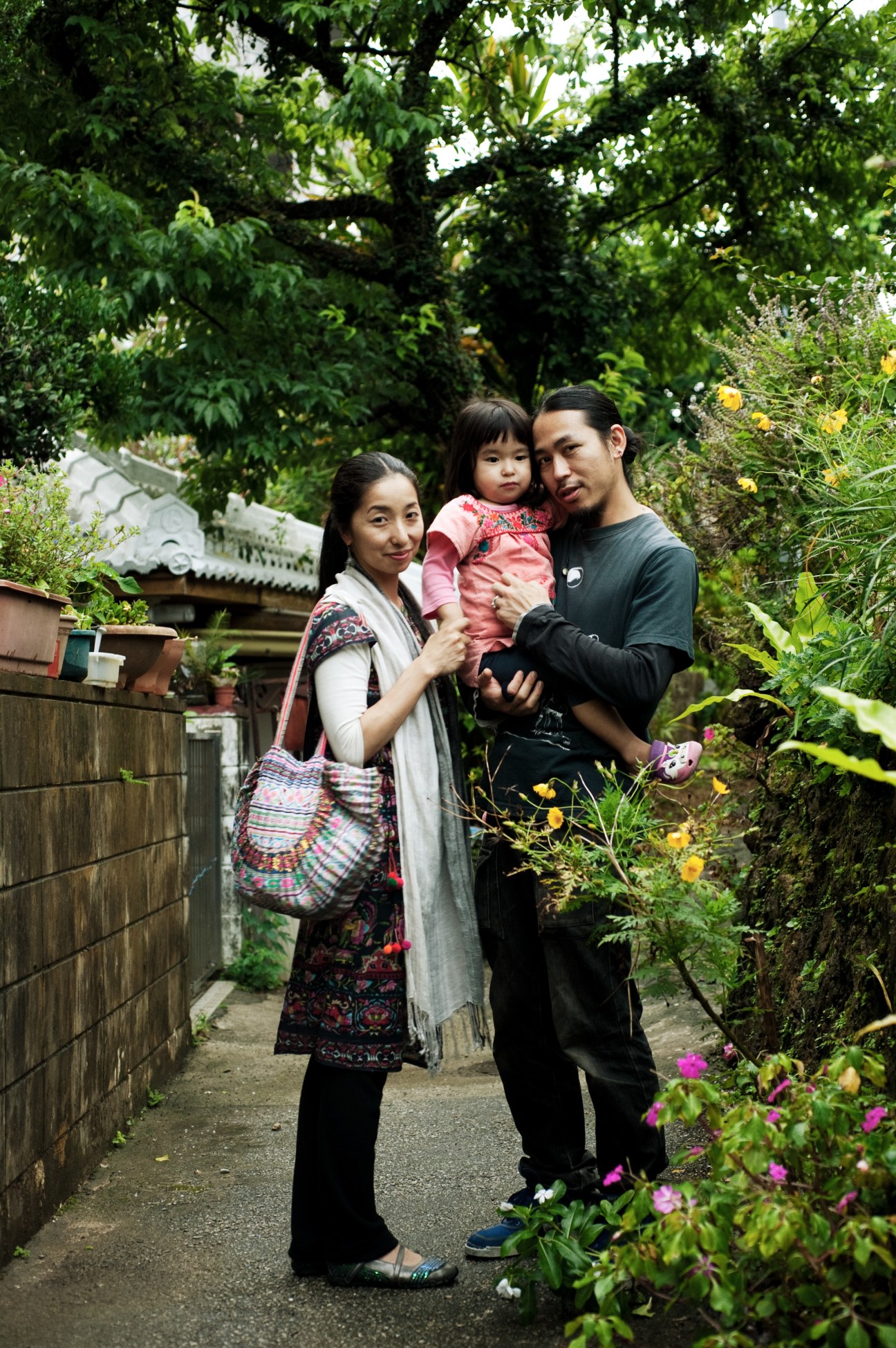 A family of three standing in a lush garden: Fukuko, Lala and Yusuke Ono of Naha.