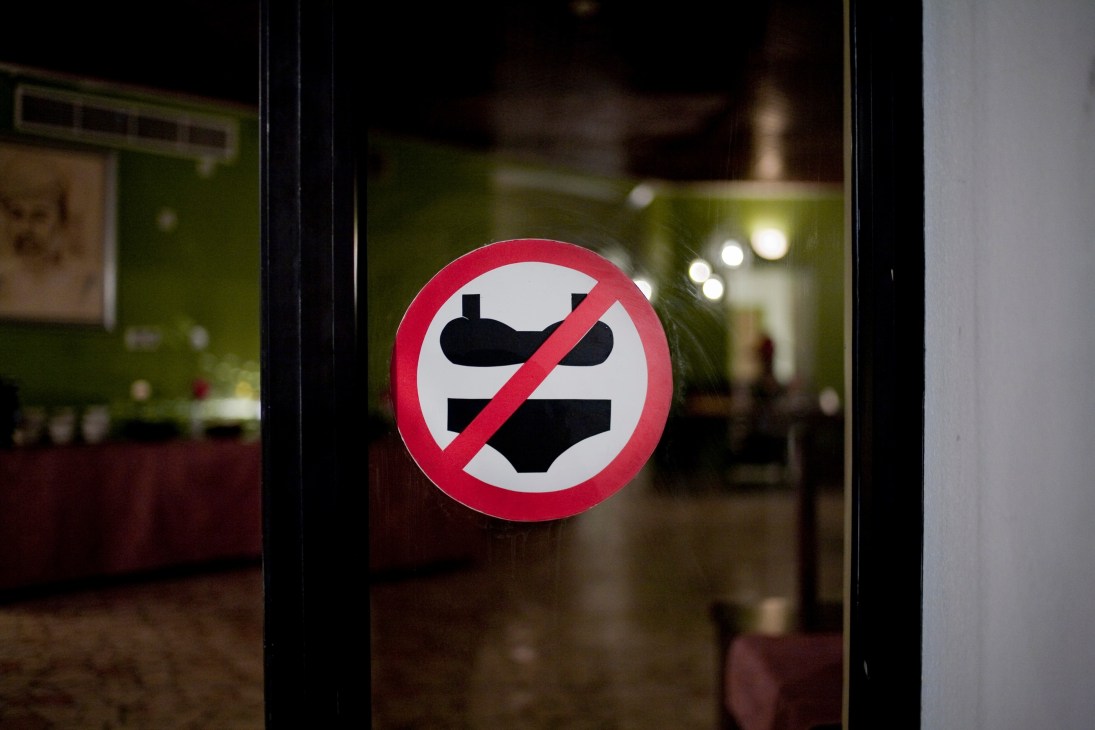 Red prohibition sign on a glass door showing banned swimwear attire.