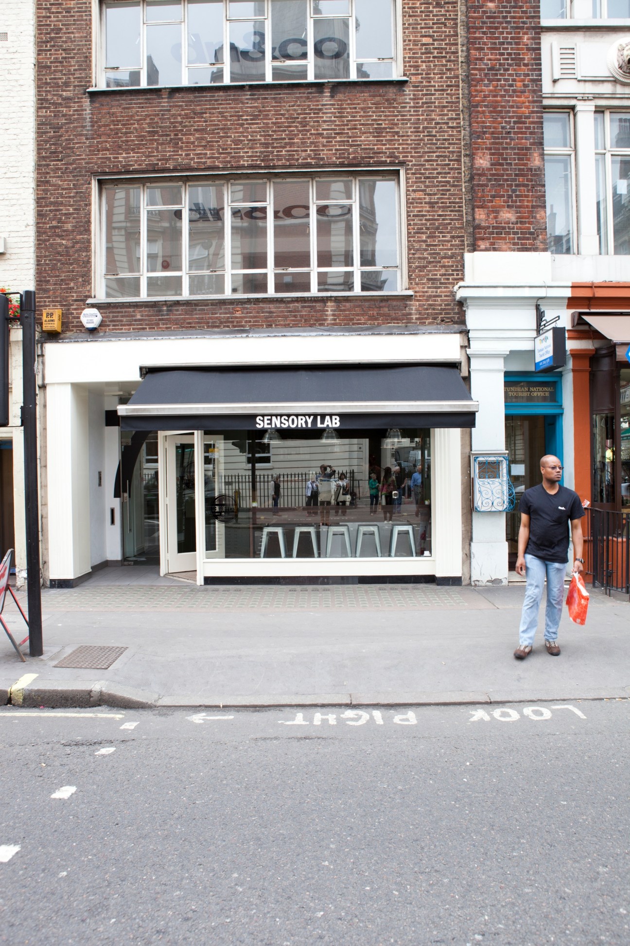 Sensory Lab coffee shop storefront on a London street with brick facade and black awning.