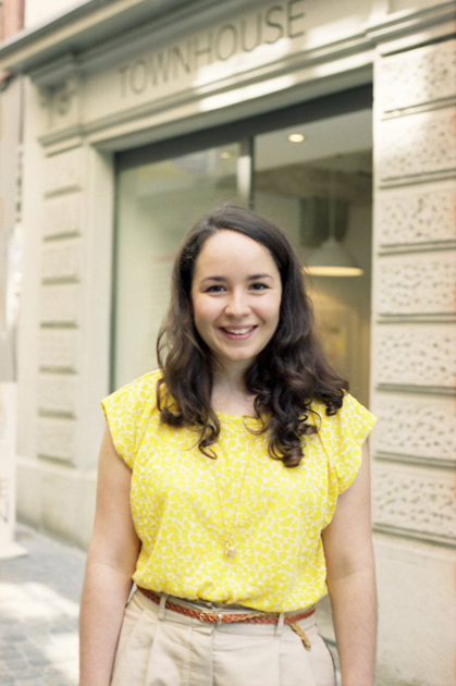 Woman in yellow patterned shirt standing outside a townhouse building
