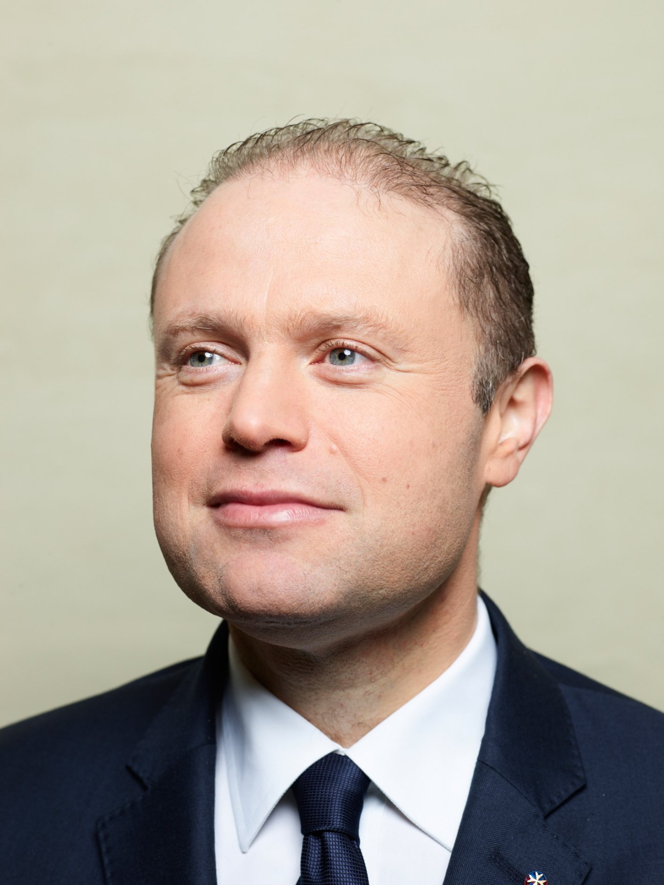 Portrait of Joseph Muscat, Malta's prime minister, wearing a dark suit and navy tie.