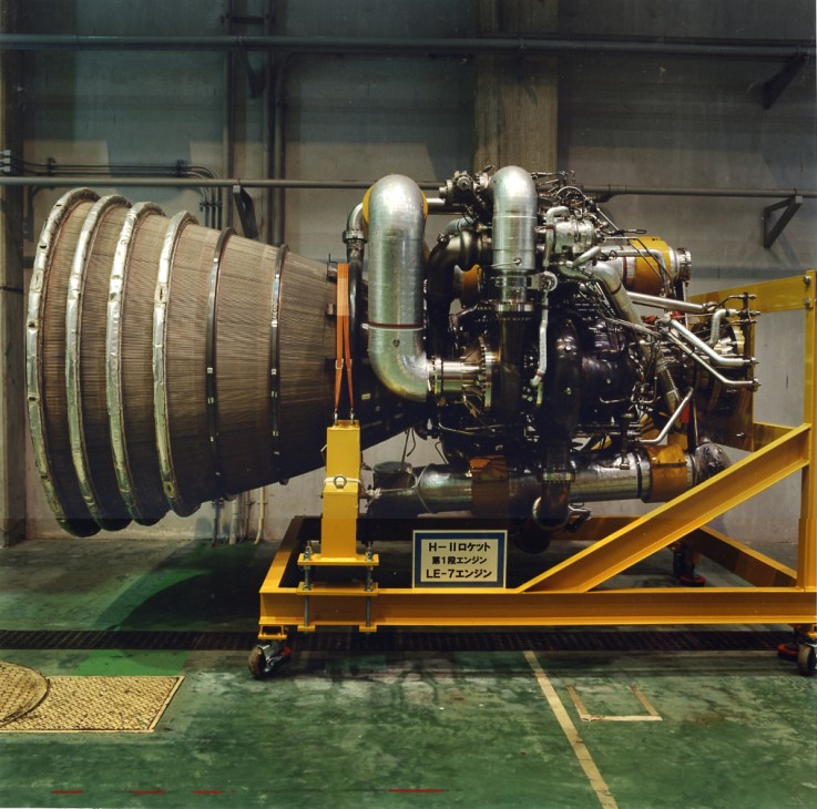 LE-7 engine on yellow display stand with coiled component and technical specifications plaque.