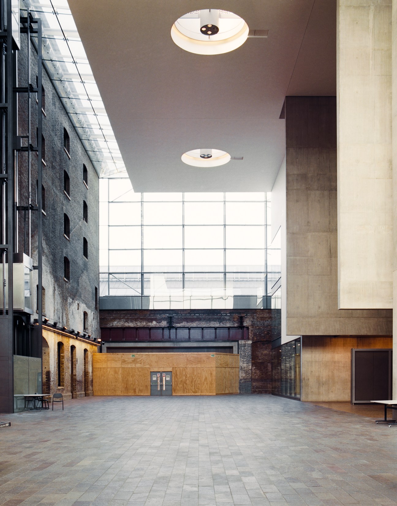 Soaring atrium of Granary Building showing industrial brick facade, modern concrete and glass with round ceiling lights.