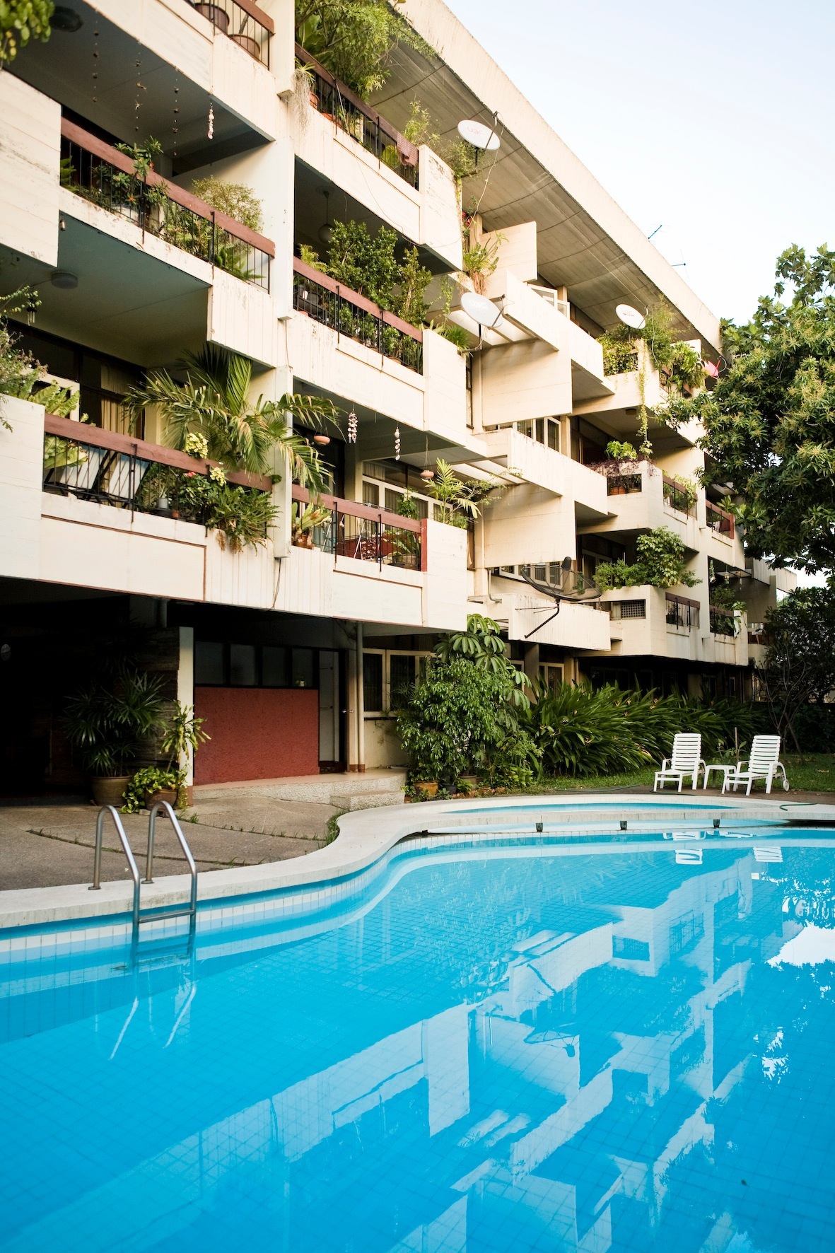 Modern apartment building with pool and green balconies in Ari neighbourhood.