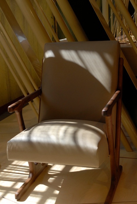 'Woody' chair by Autoban for De La Espada with cream upholstery and wooden frame in sunlight.