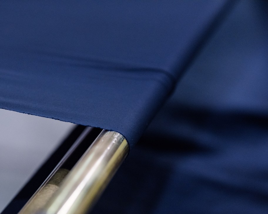Blue fabric being smoothed on a work surface with a metal roller tool.